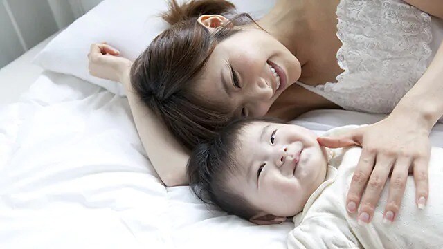 Smiling infant and woman lying down