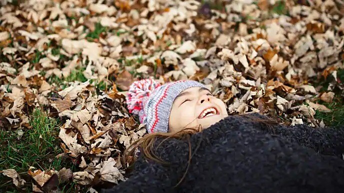 Smiling child lying on leaves