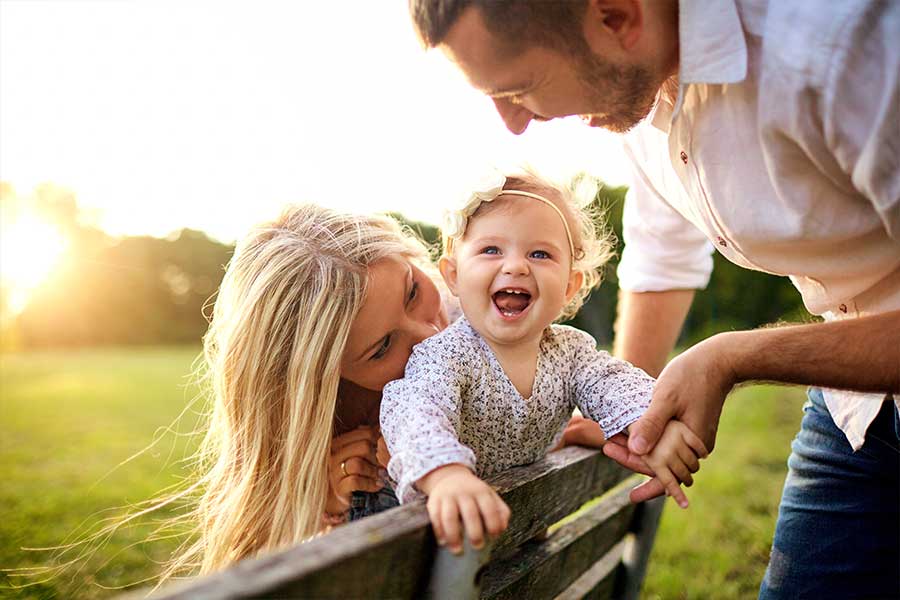 Happy family outside with laughing baby enjoying the sunrise