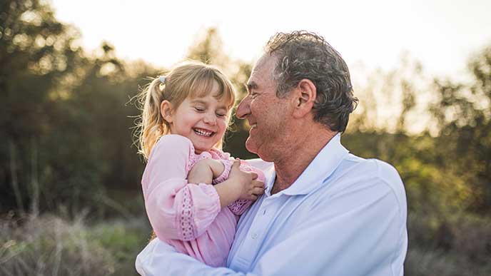 Grandpa holding granddaughter in field and laughing Grandpa holding granddaughter in field and laughing