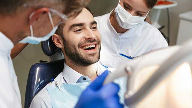 happy young man sitting in medical dental chair ready for treatment