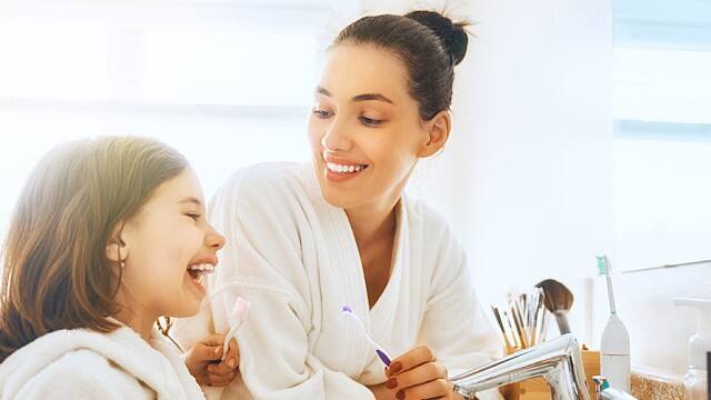 mother and daughter prepare to floss at home