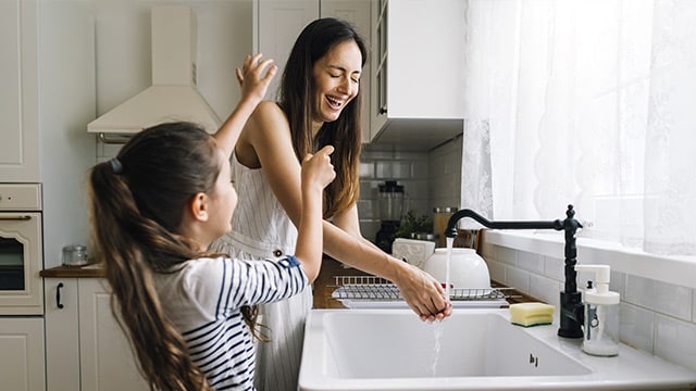 Mother and daughter washing dishes and having fun together