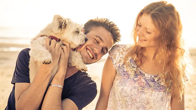 Smiling woman looking at a man holding a dog