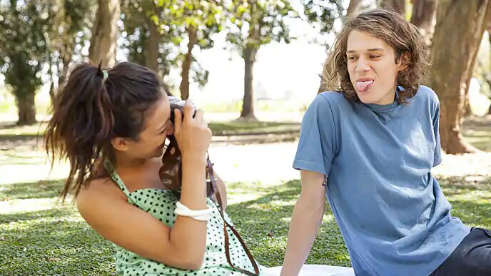 A woman taking a photo of a man with his tongue sticking out