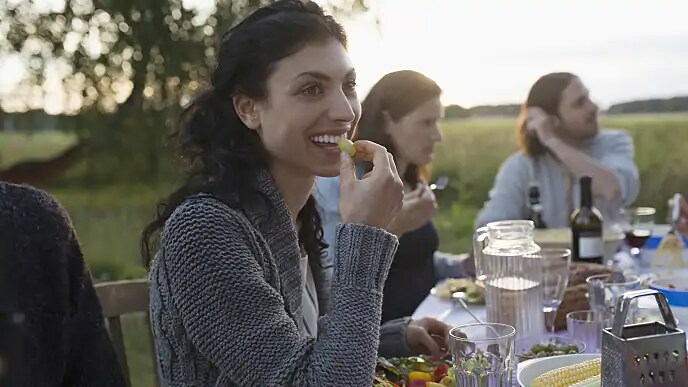 A woman smiles as she eats a grape