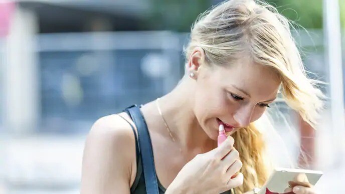 woman putting on lipstick