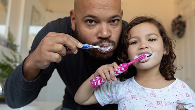 Hombre y niña cepillando sus dientes