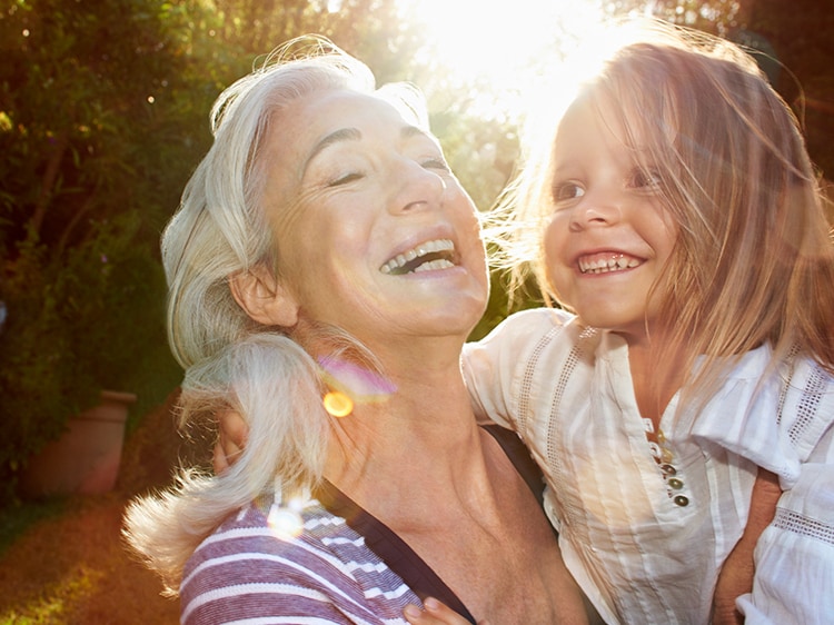 An elderly woman hold a child outdoors