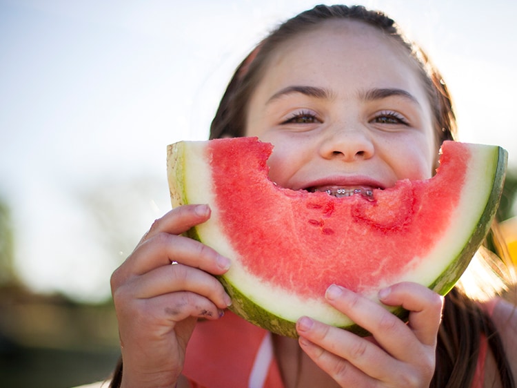 child with braces eating watermelon