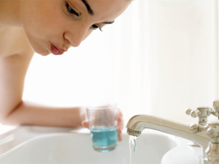 woman using colgate dental rinse
