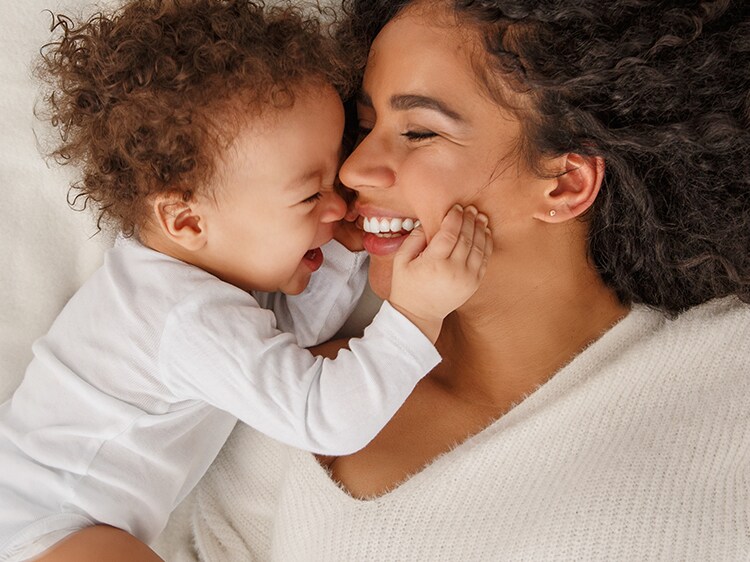 smiling woman and infant on a bed