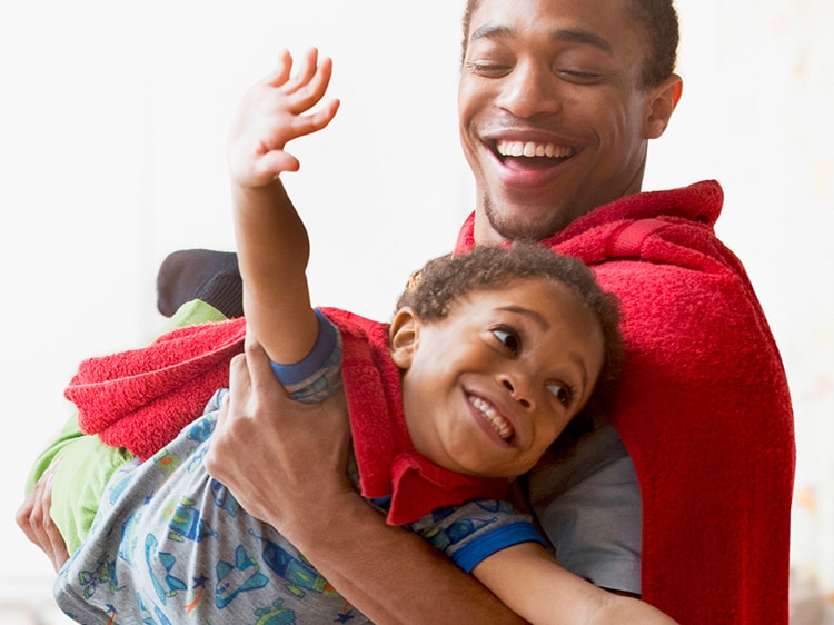 smiling man playing superhero with son