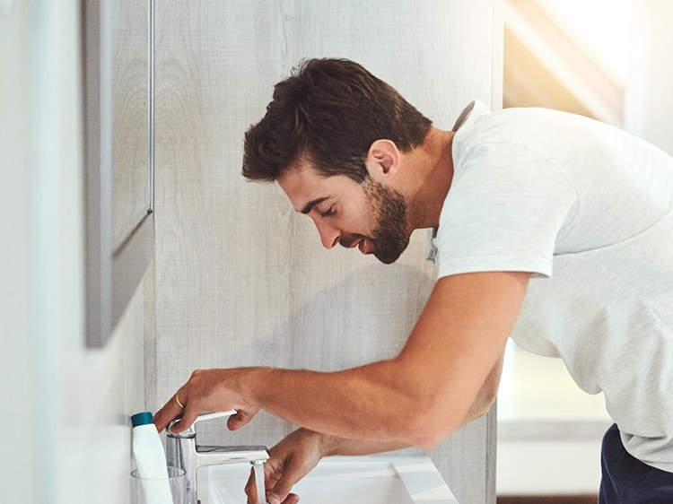 man brushing his teeth at a sink