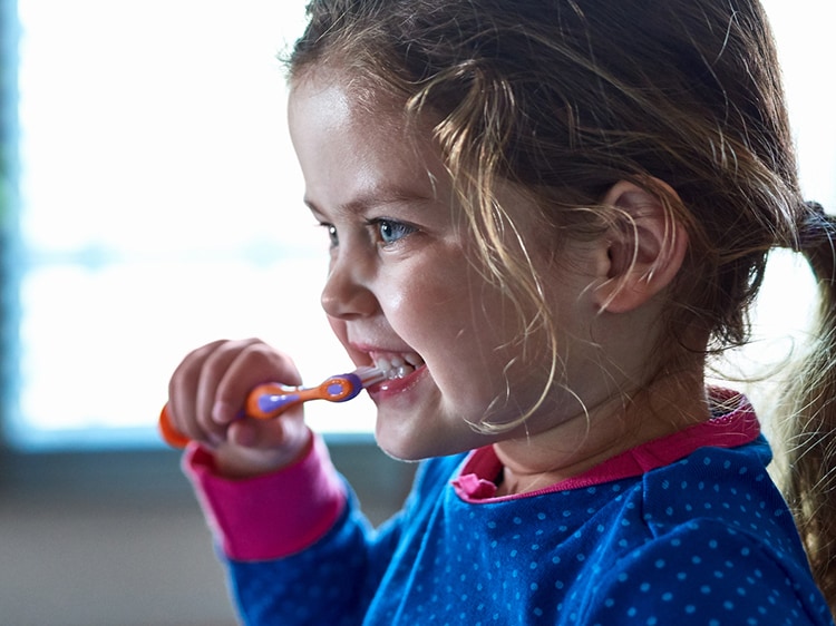 young girl using colgate toothbrush