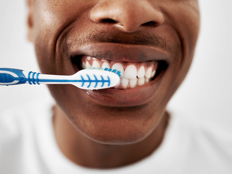 Hombre cepilla sus dientes con cepillo colgate