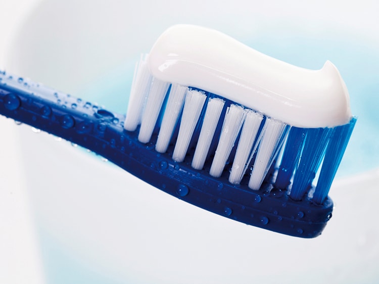 close up of colgate toothpaste on blue toothbrush