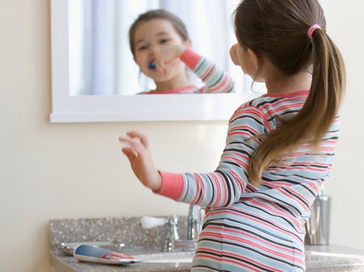 Mixed race girl brushing teeth.