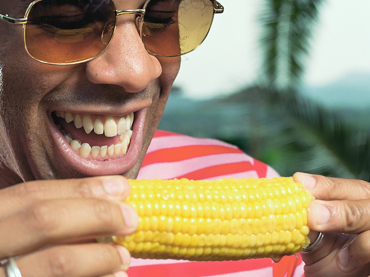 close up of man about to eat ear of corn