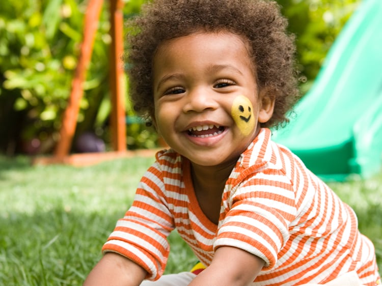 toddler with face paint smiling outside