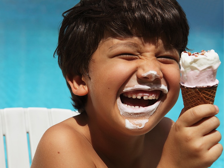 smiling boy eating and wearing ice cream on his face