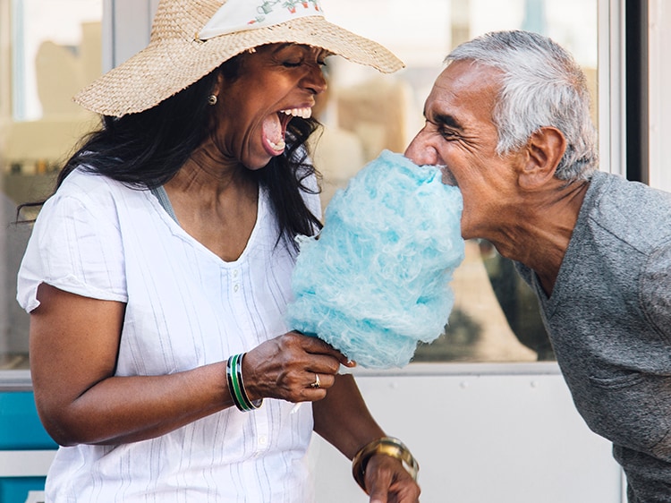 laughing woman feeding cotton candy to man