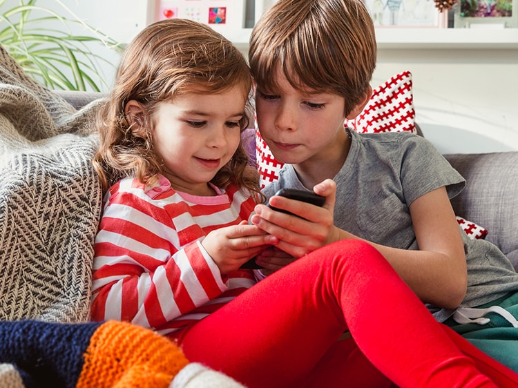 children looking at a smartphone on a sofa