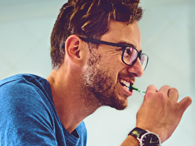 man brushing his teeth with colgate toothbrush