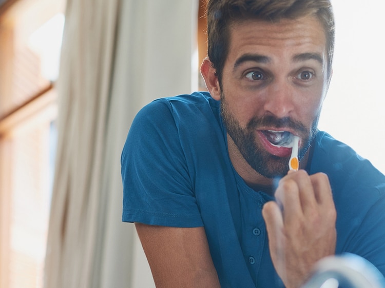 man brushing his teeth with colgate toothbrush
