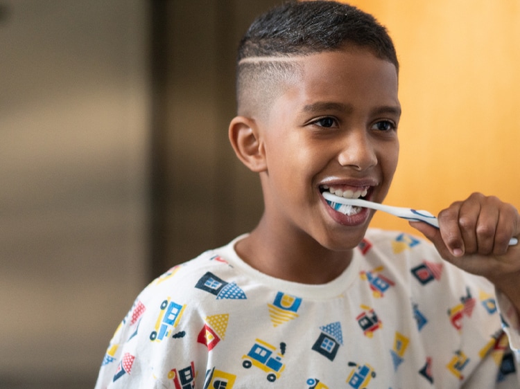 boy using colgate toothbrush while brushing teeth