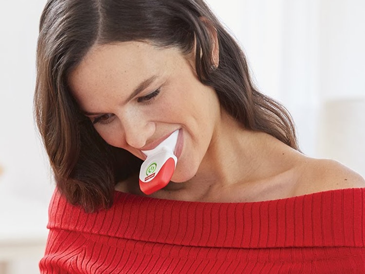 woman in red using colgate tooth whitening device