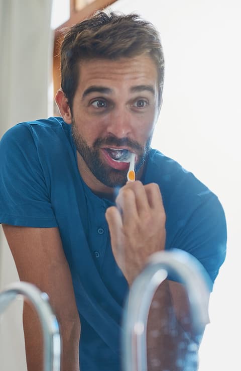 hombre usando cepillo de dientes colgate