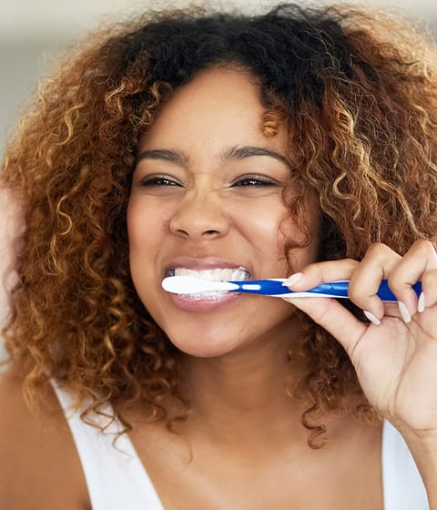 mujer usando cepillo de dientes colgate