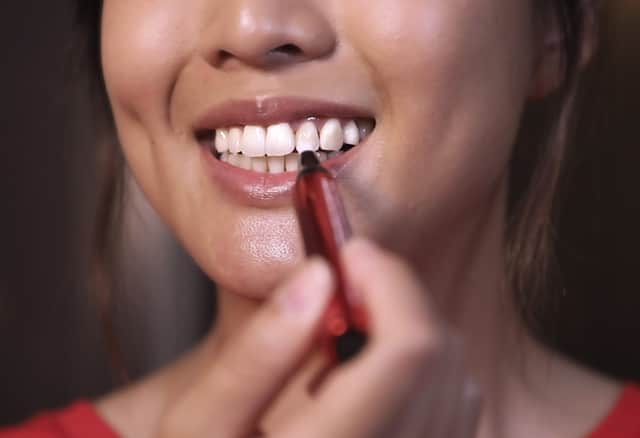 Lady applies the Colgate's Optic White O2 Teeth Whitening serum onto teeth