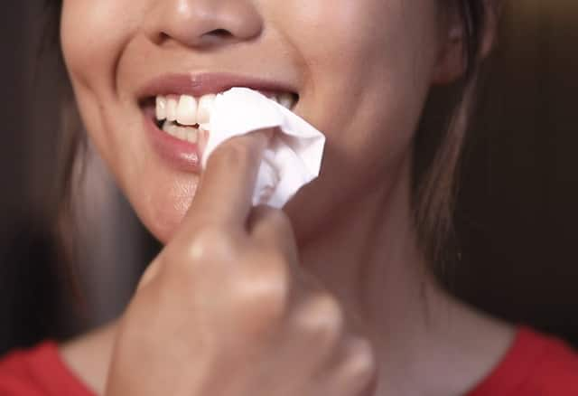 Lady is drying her teeth in preparation for the Colgate's teeth whitening routine 