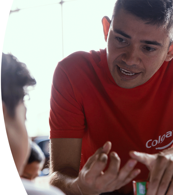 En la imagen vemos a Fernando, que es un odontólogo voluntario de Colgate, enseñándole a un niño buenos hábitos de salud bucal.