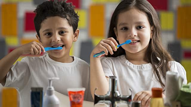a girl and a boy brushing with Colgate toothbrush