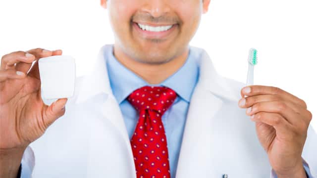 Dentist holding toothbrush and explaining the importance of fluoride in toothpastes
