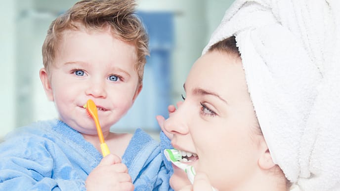 mother teaches her little son how to brush