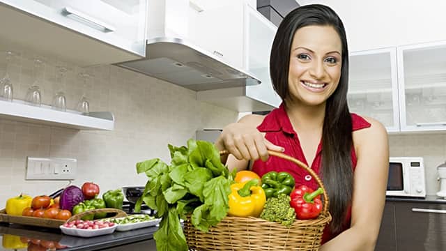 woman smiling holding a basket of vegetables