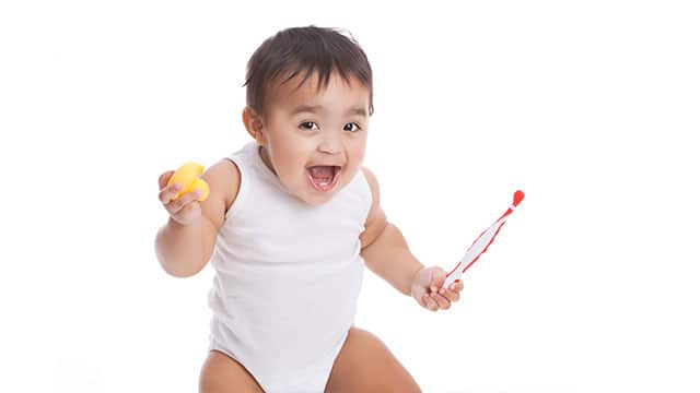 Adorable mixed race baby boy holding toothbrush