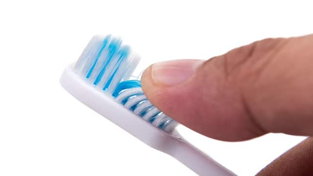 Finger touching the soft slim toothbrush