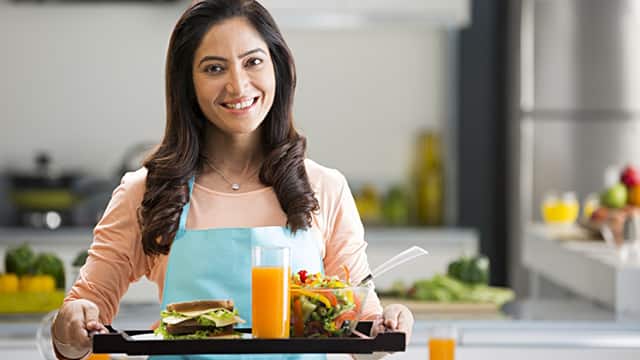 woman smiling holding a tray of food and drink