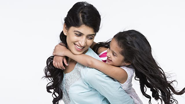 mother smiling giving her daughter a piggyback ride