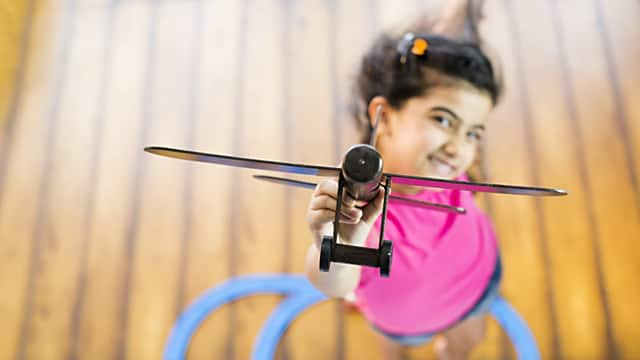 a girl smiling holding an airplane toy