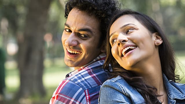 a man and a woman leaning on each other while smiling