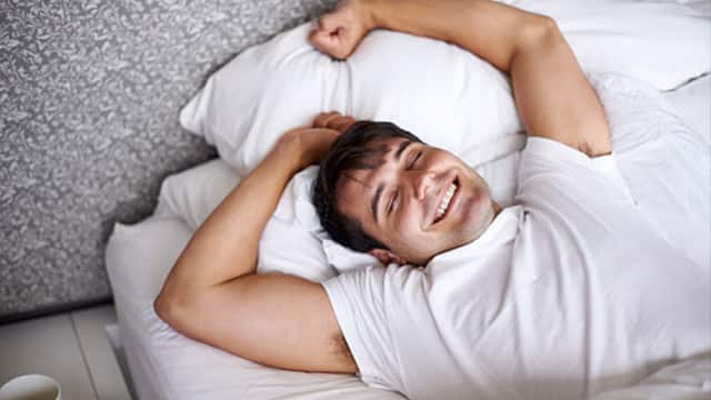 man smiling in bed waking up