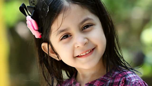 a girl wearing a ribbon smiling brightly