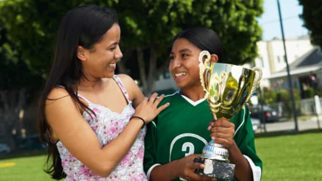 A mother and child smiling while holding a trophy