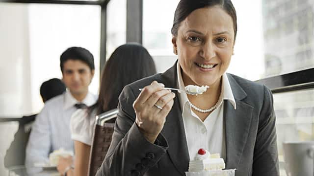 a woman smiling while eating a cake